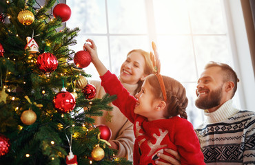 happy family mother, father and child daughter decorate christmas tree .