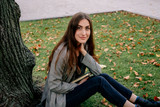 Fototapeta Młodzieżowe - Beautiful young student girl sitting on the lawn in the university park. 