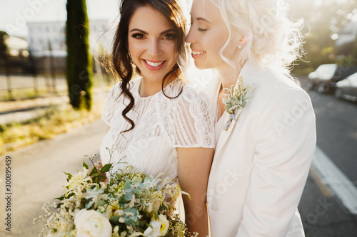 Cuadros en Lienzo Just married lesbian couple is hugging outdoors and holding big bridal bouquet