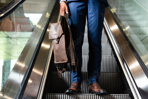 Photographie cropped view of man holding backpack on escalator in hotel