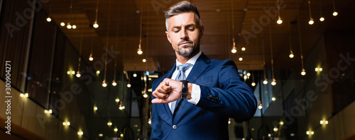 Fotomural panoramic shot of businessman in suit looking at watch