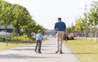 © Syda Productions - family, leisure and fatherhood concept - happy father spending time with little son riding scooter in city