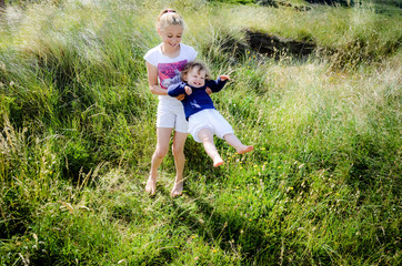 Canvas Print - two pretty sisters playing together in tall grass