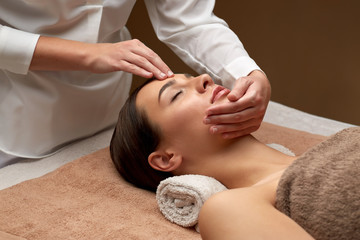 Poster - wellness, beauty and relaxation concept - beautiful young woman lying with closed eyes and having face and head massage at spa