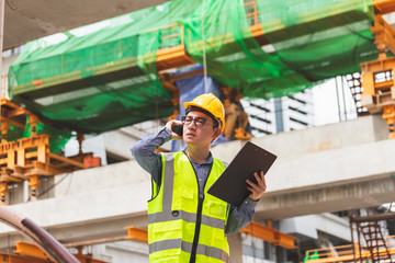 Wall Mural - Image outside the industrial construction engineers in yellow protective helmet discuss new project while walkie talkie and happy smile on the open building site near the crane.