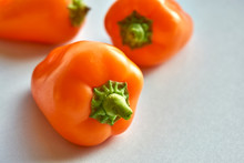 Small Bell Peppers. Three Orange Mini Peppers On A Light Blue Background With Copy Space.