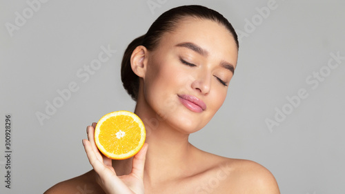 Cuadros en Lienzo Beautiful pretty woman holding half of orange
