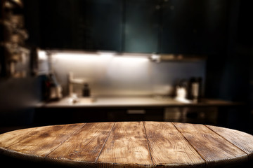 Wooden table background of free space for your decoration and blurred background of kitchen. Copy space.Dark mood interior. Kitchen furniture. 