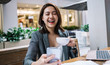 © BullRun - Young Asian female with cup laughing and using smartphone