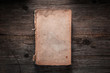 © solidmaks - Closed book on vintage wooden background.  Old book on the wooden table. Closed book with empty cover laying on wooden table.