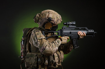 a male soldier in military clothes with a weapon on a dark background