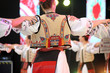 Dancers hold hands in a traditional Romanian dance wearing traditional beautiful costumes.