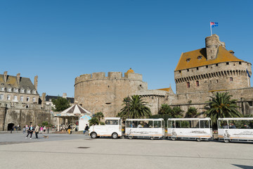 Poster - tourist sightseeing train waits for passengers outside the city walls of the old town of Saint-Malo in Brittany