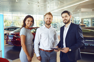 Wall Mural - A couple buys a new car. A man and a car salesman make a handshake