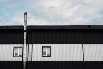 Black and white Corrugated metal sheet texture surface on a building wall with windows. Galvanize steel background.