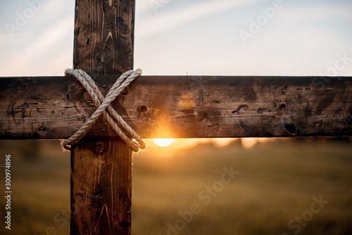 Fotomural Closeup shot of a wooden cross with the sun in the blurred background
