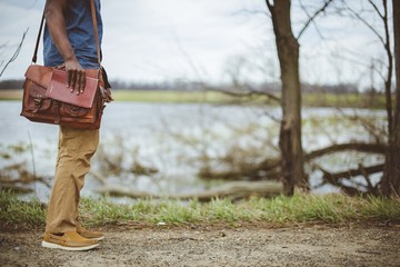 Canvas Print - Male standing near a lake while holding the bible with a blurred background