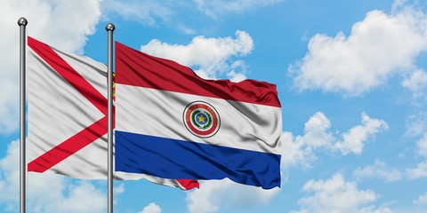 Jersey and Paraguay flag waving in the wind against white cloudy blue sky together. Diplomacy concept, international relations.