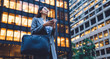 © BullRun - Young female with smartphone standing by skyscraper