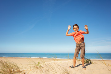 Wall Mural - Cute boy jump on the sand dune at sea beach