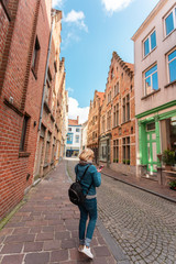 Wall Mural - Woman tourist lost in the streets of the city and is looking on his phone how to get further, Bruges, Belgium