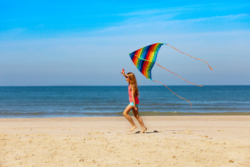 Wall Mural - Profile portrait of girl run with kite on a beach