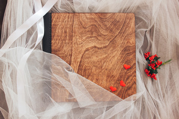 Wall Mural - Wood and leather photo book on white cloth. A book with a wooden cover top view with hearts