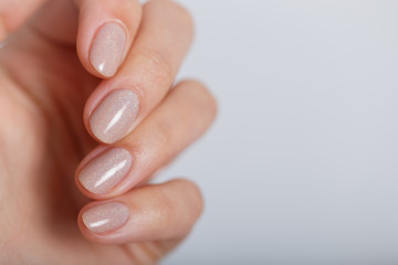 Wall Mural - Nude color manicure on short round natural nails on the pure grey background