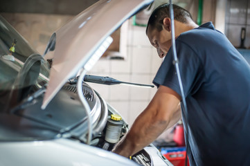 Wall Mural - Car mechanic repairer service technician checks and repairs auto engine