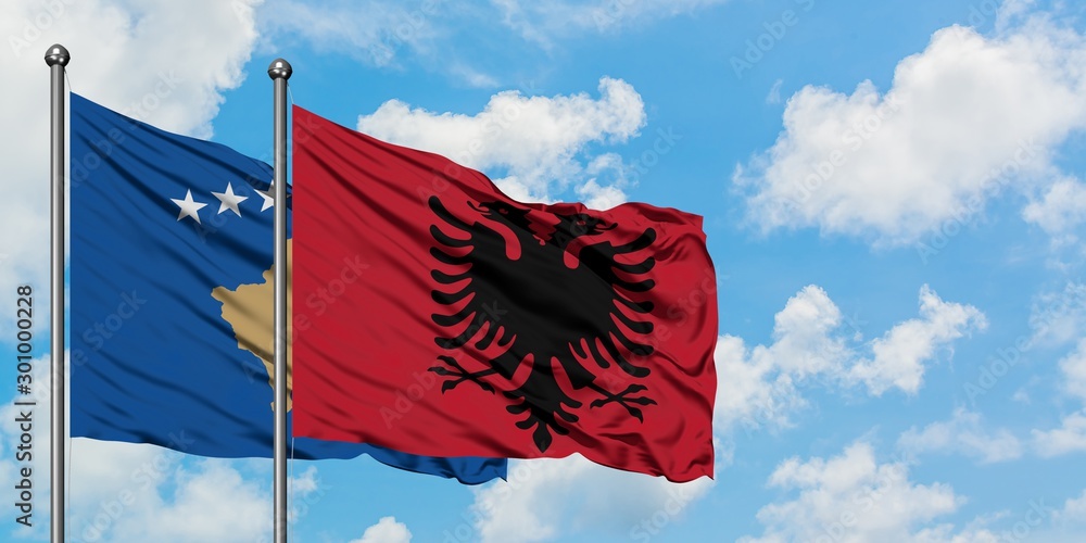 Kosovo and Albania flag waving in the wind against white cloudy blue ...