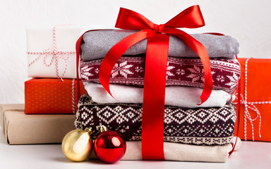 Many bright Christmas sweaters with patterns wrapped by red bow