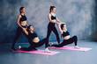 © BullRun - Group of caucasian attractive women practicing yoga indoors stretching flexibility pose during workout, four slim positive hipster girls in black sportswear enjoying healthy training at fitness studio