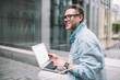 © BullRun - Inspired young man sitting with laptop on street