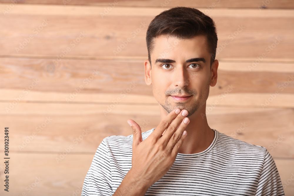 Young deaf mute man using sign language on wooden background