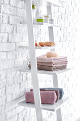 Poster - Shelf with towels and cosmetics near white brick wall in bathroom