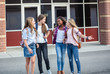 Leinwandbild Motiv Candid photo of a group of teenage girls socializing, laughing and talking together at school. A multi-ethnic group of real junior high aged students walking outside a school building