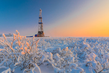 Wall Mural - In a winter snow-covered tundra, a well is being drilled at an oil and gas field. Polar day. Beautiful sky. The drilling rig is covered in snow.