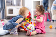 © Oksana Kuzmina - Child girl taking toy away another kid. Babies adaptation in kindergarten
