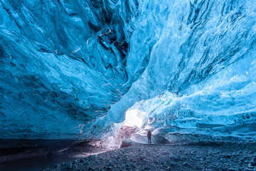 tourist standing in an ice cave in vatnajökull glacier iceland
