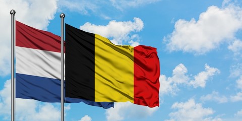 Wall Mural - Netherlands and Belgium flag waving in the wind against white cloudy blue sky together. Diplomacy concept, international relations.
