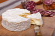 cow's milk french cheese called camembert and pork dry sausage on cutting board