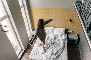 Canvas Print - Young girl relaxing on comfy bed in modern hotel room