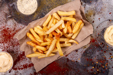 French Fries Chips Potato And Sauces On Black Stone Slate Over Rusty Background. Top View