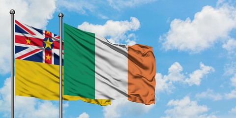 Niue and Ireland flag waving in the wind against white cloudy blue sky together. Diplomacy concept, international relations.