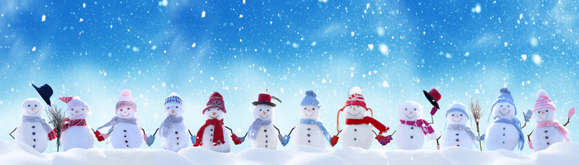 Wall Mural - Merry Christmas and happy New Year greeting card with copy-space.Many snowmen standing in winter Christmas landscape.Winter background