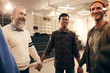 © AnnaStills - Group of happy people standing holding hands and smiling to each other during business training at office