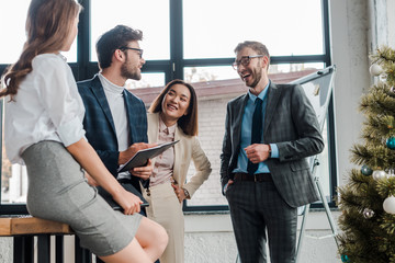 Wall Mural - selective focus of happy businessmen and businesswoman near christmas tree in office