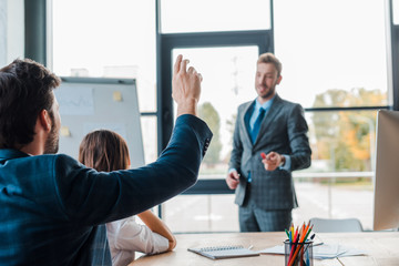 Wall Mural - selective focus of businessman raising hand near speaker and businesswoman in office