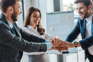 Wall Mural - selective focus of happy businessmen and businesswoman putting hands together