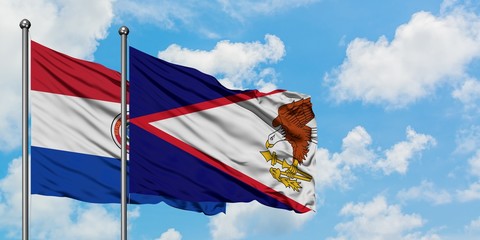 Paraguay and American Samoa flag waving in the wind against white cloudy blue sky together. Diplomacy concept, international relations.
